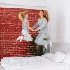 A woman and a child joyfully jumping on a bed, capturing a moment of playful bonding and happiness.