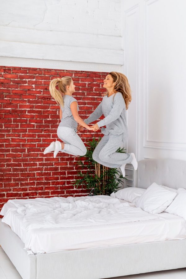 A woman and a child joyfully jumping on a bed, capturing a moment of playful bonding and happiness.